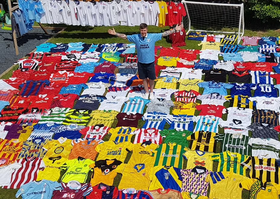 A football shirt collector standing among hundreds of retro football shirts on a lawn